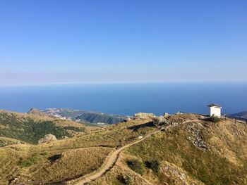 Scenic view of sea and mountains against clear blue sky