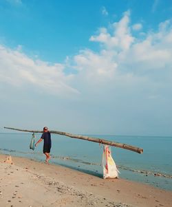 Boy on beach by sea against sky