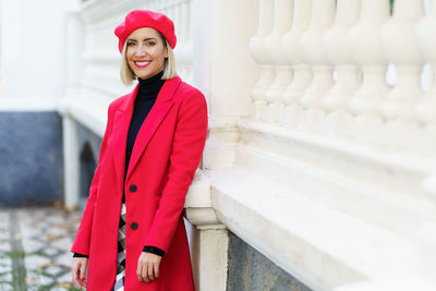 Portrait of young woman standing against wall