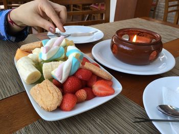 Cropped hand of woman having food at table