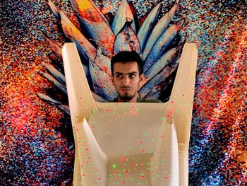 Portrait of young man standing against multi colored wall