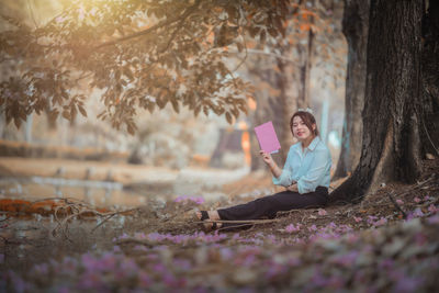 Woman sitting on tree trunk