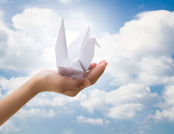 Midsection of person holding paper against sky