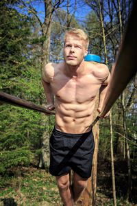 Shirtless man exercising in forest