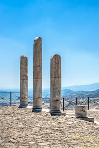 Wooden posts on beach against blue sky