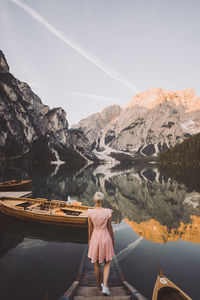 Rear view of woman standing on mountain by lake against sky