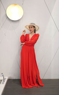 Young woman with red umbrella standing against the wall