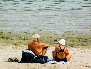 Rear view of men sitting on beach
