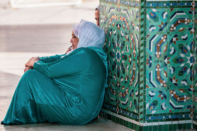 Side view of woman sitting on floor