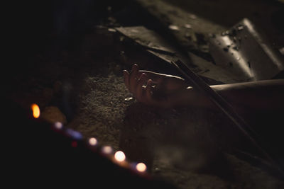 Close-up of hand lying on ground at night