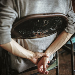 Midsection of man with hands behind back sitting on chair