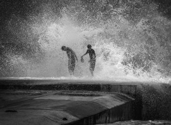 Friends standing in splashing sea