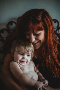 A mother holding a baby with joy and laughter in home on pretty chair