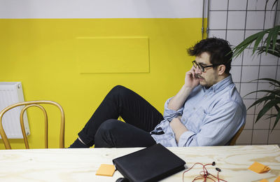 Young man using smart phone while sitting at desk in board room