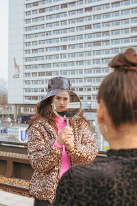 Woman showing mirror to friend in city