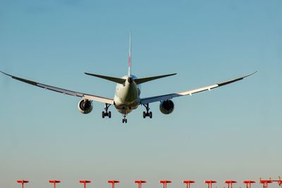 Low angle view of airplane flying against clear blue sky