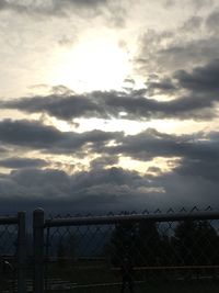 Cloudy sky seen through chainlink fence