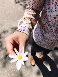 Low section of man holding flower while standing on street