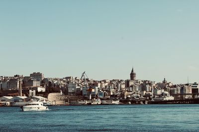 Sea by buildings against clear sky