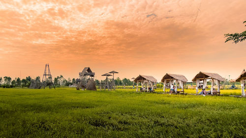 Houses on field against sky during sunset