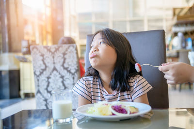 Asian child girl with expression of disgust against tomato in salad,