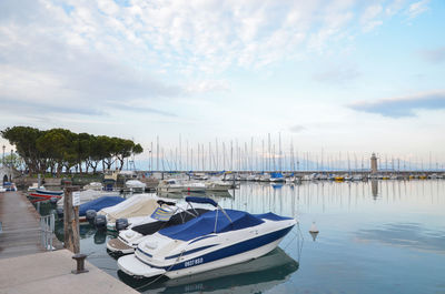 Boats moored at harbor against sky