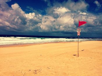 Lighthouse on beach against cloudy sky