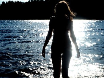 Rear view of woman standing at beach