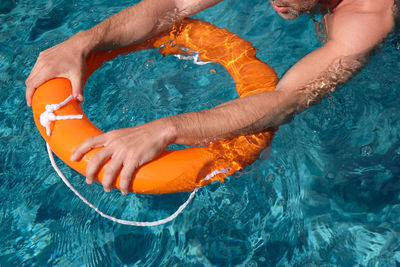 Cropped hands of man holding life belt in pool