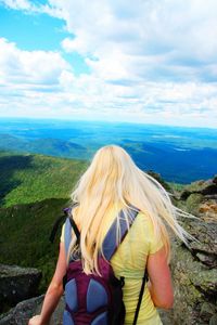 Rear view of woman standing on mountain against cloudy sky