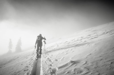 Rear view of people on snowcapped mountain against sky