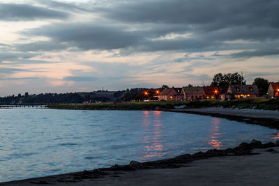 View of city at waterfront against cloudy sky