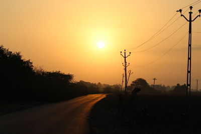 Silhouette people riding motorcycle on road against sky during sunset