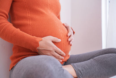 Midsection of woman touching mirror
