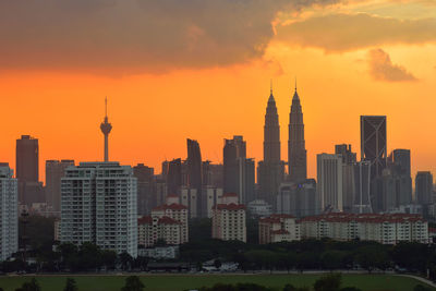 Menara kuala lumpur and petronas towers against sky during sunset in city