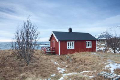 Houses on snow covered land by sea against sky