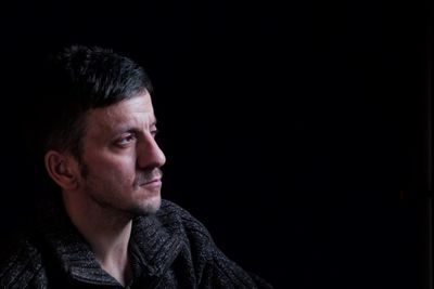 Portrait of young man against black background