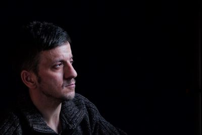 Portrait of young man against black background