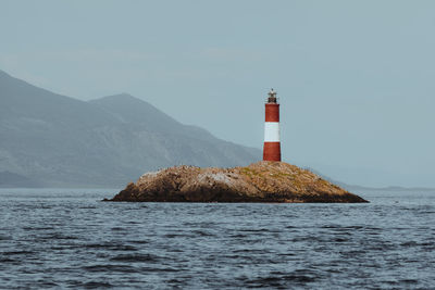 Lighthouse by sea against sky