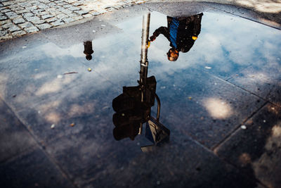 Reflection of woman in puddle on street