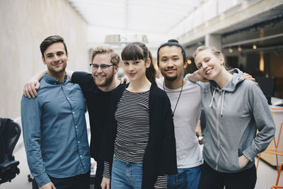 Group portrait of confident male and female computer programmers standing together in office