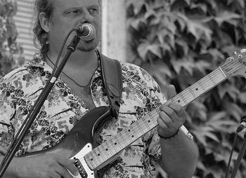 Man playing guitar while singing outdoors