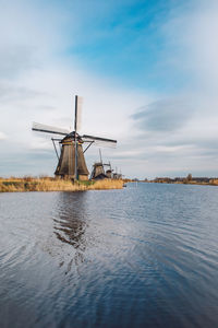 Traditional windmill on shore against sky