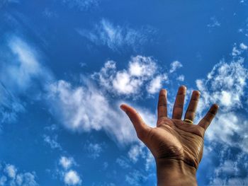 Low angle view of hand against blue sky