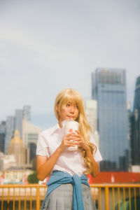 Portrait of young woman standing against buildings