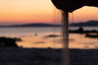 Close-up of silhouette beach against sky during sunset