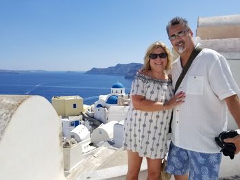 Portrait of smiling mature couple in town against sea during sunny day