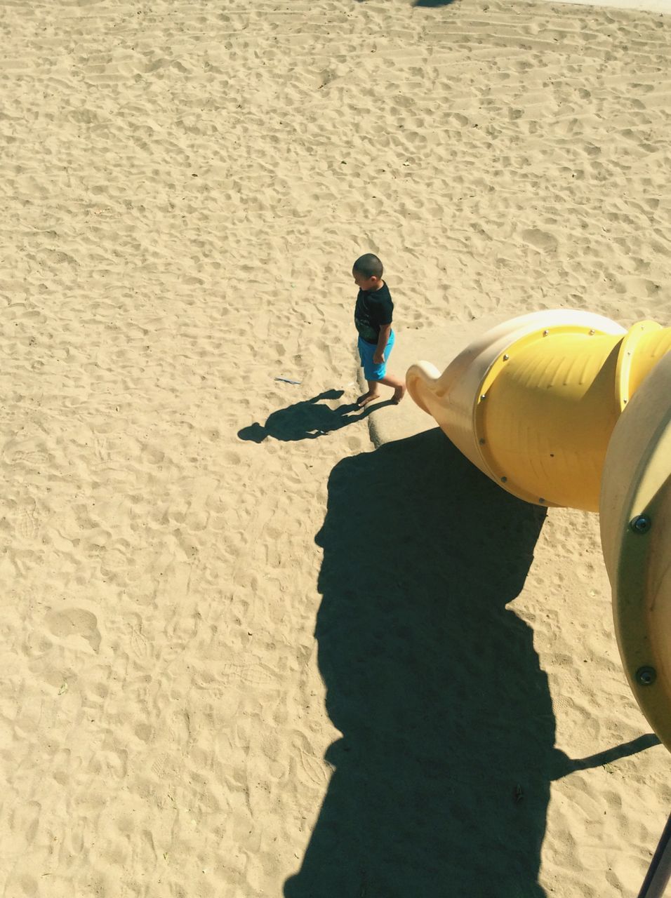 lifestyles, leisure activity, full length, shadow, sunlight, men, casual clothing, built structure, outdoors, day, holding, childhood, architecture, rear view, street, yellow, building exterior, high angle view