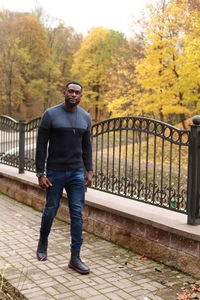 Full length portrait of young man standing on footpath