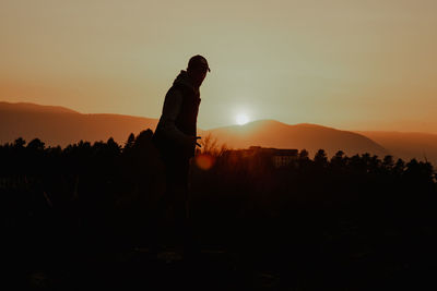 Silhouette man standing on field against sky during sunset